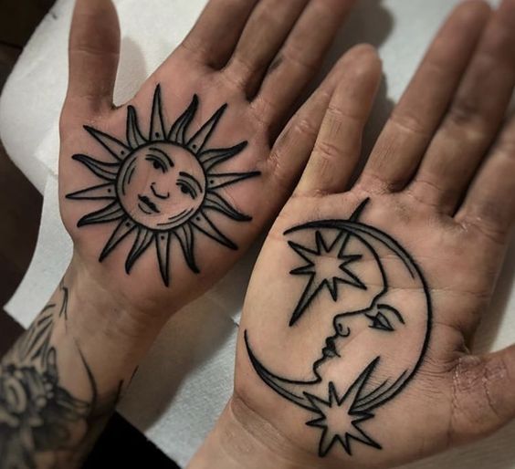 two hands with sun and moon tattoos on them