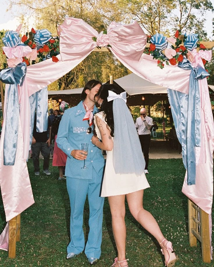 a man and woman kissing in front of a wedding arch