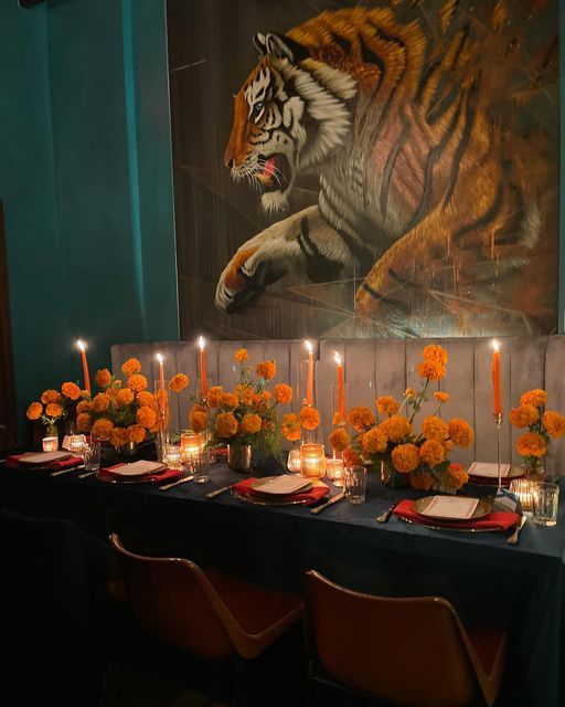 the table is set with orange flowers and candles