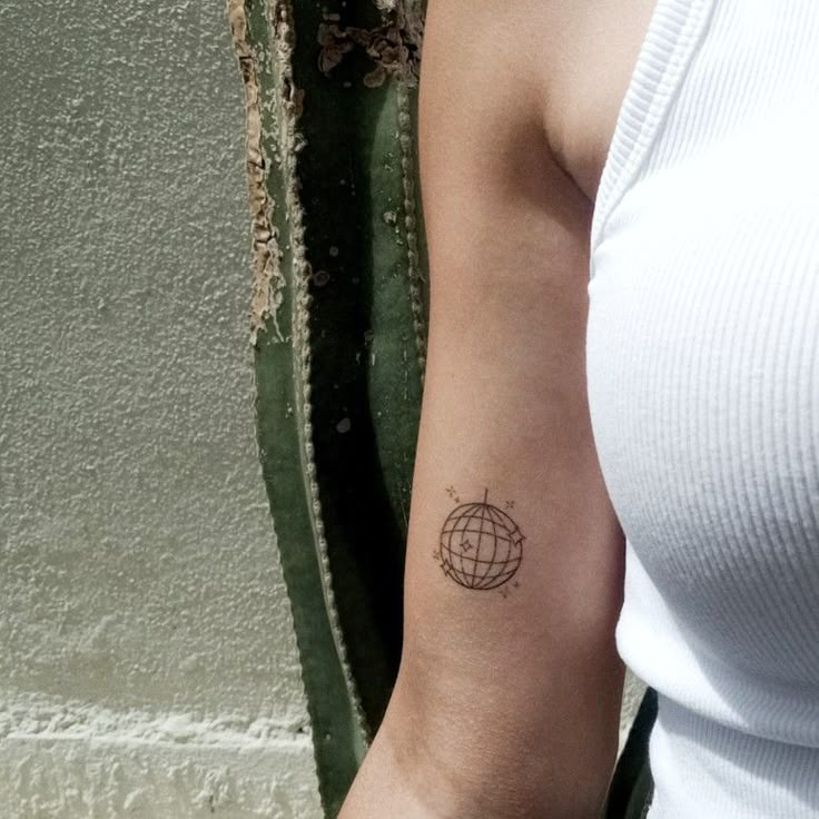 a woman's arm with a small globe tattoo on the left side of her arm