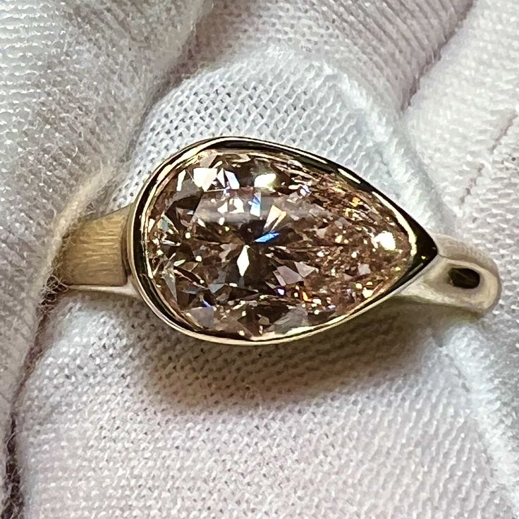 a fancy ring is sitting on top of a white towel with a diamond in the center