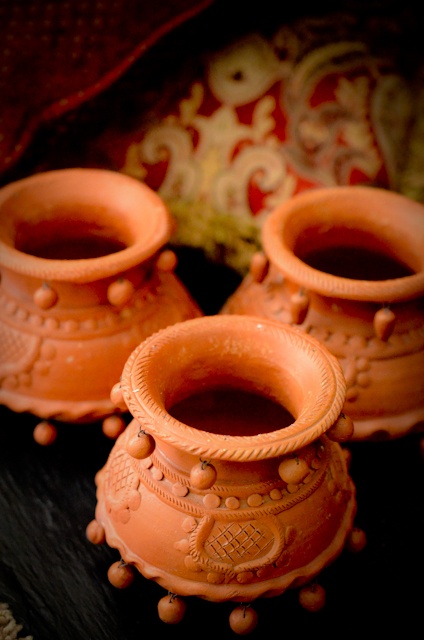 three orange vases sitting on top of a black table next to a red pillow