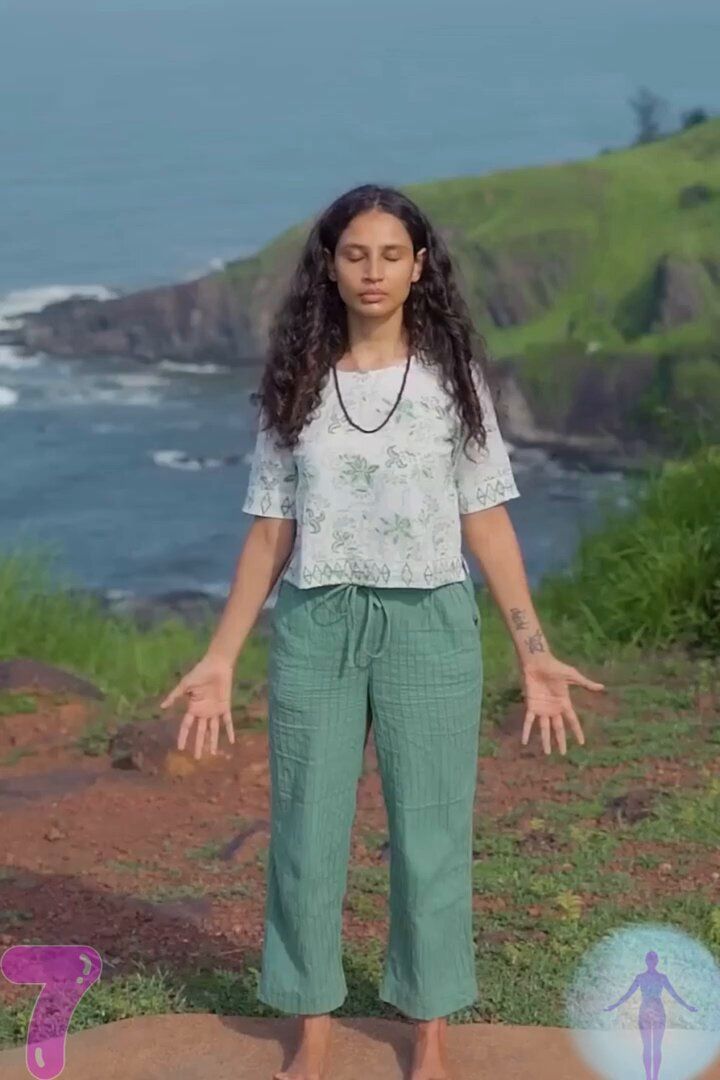 a woman standing on top of a rock near the ocean