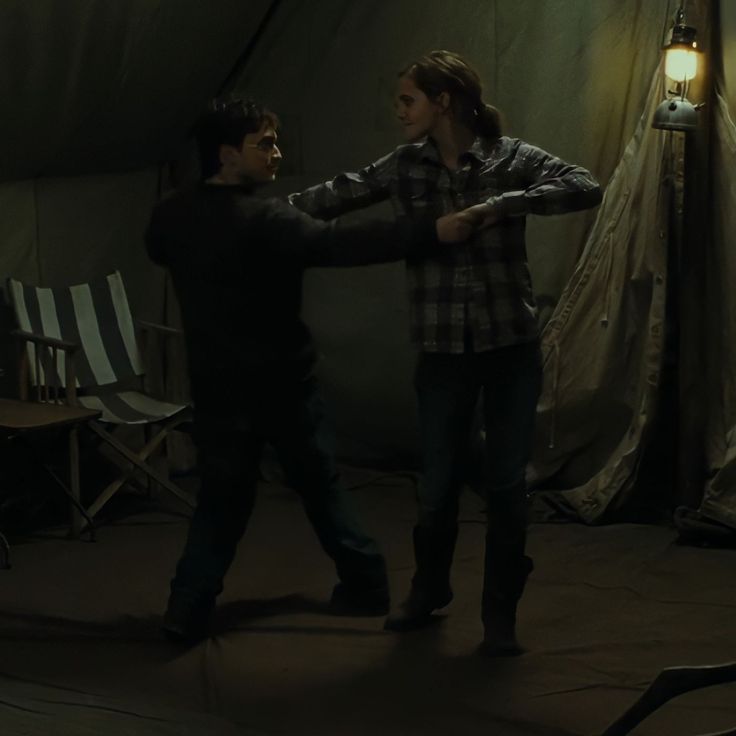 two people standing in a tent with one holding the other's hand and another pointing at him