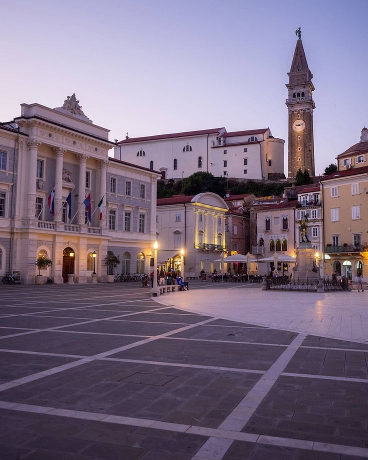 an empty square in front of some buildings with a clock tower at the far end