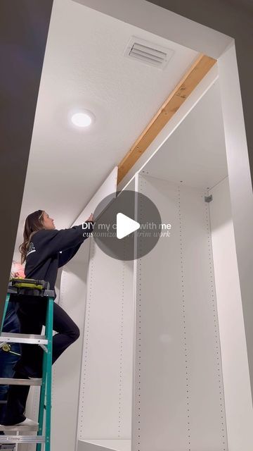 a man on a ladder working on the ceiling in a room with white walls and ceilings