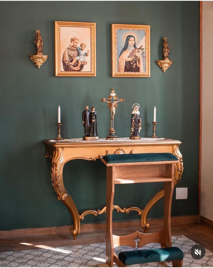 a table with candles and pictures on the wall above it in a room that has green walls