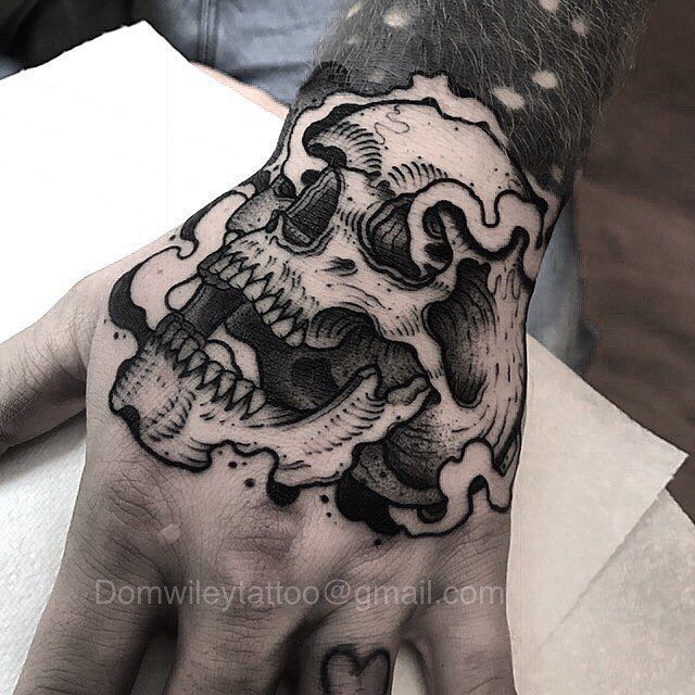 a man's hand with a black and white tattoo on it