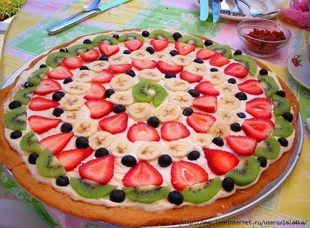 a fruit pizza with kiwis, strawberries, and bananas on the top