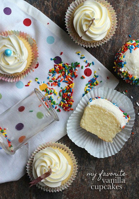 several cupcakes with white frosting and sprinkles on a table