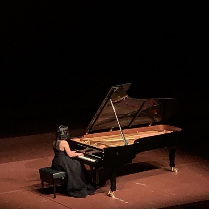 a woman sitting at a piano in the dark