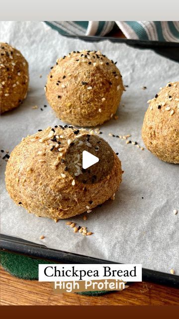 four balls of bread sitting on top of a baking sheet next to a pan filled with sesame seeds