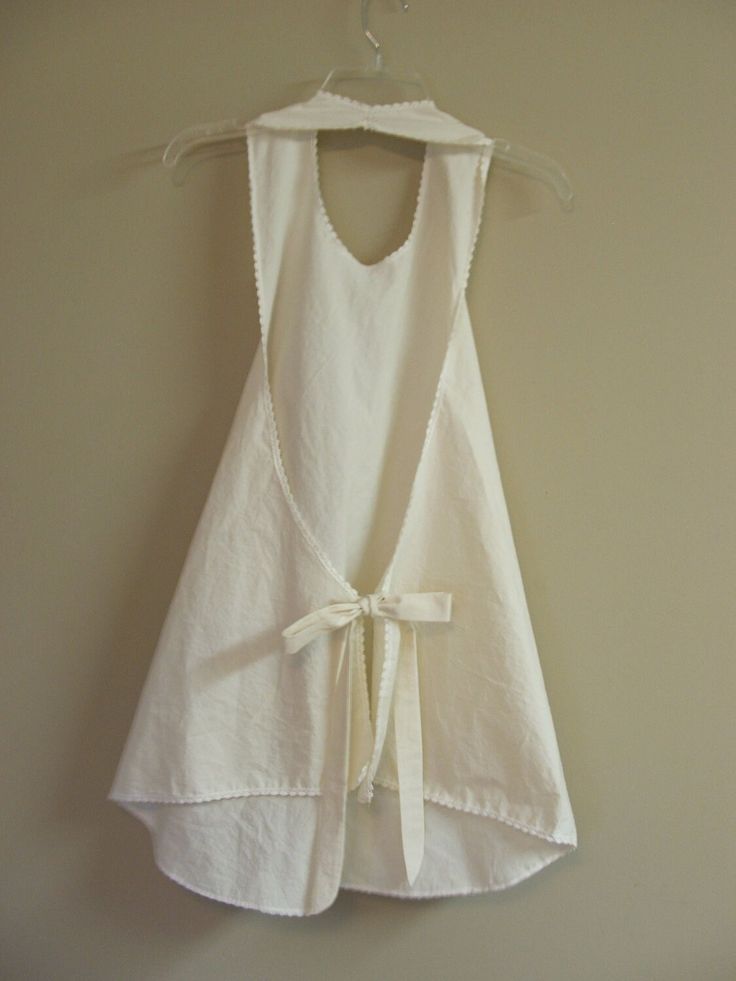 a white dress hanging on a wall with a hanger in front of it that has a bow at the waist