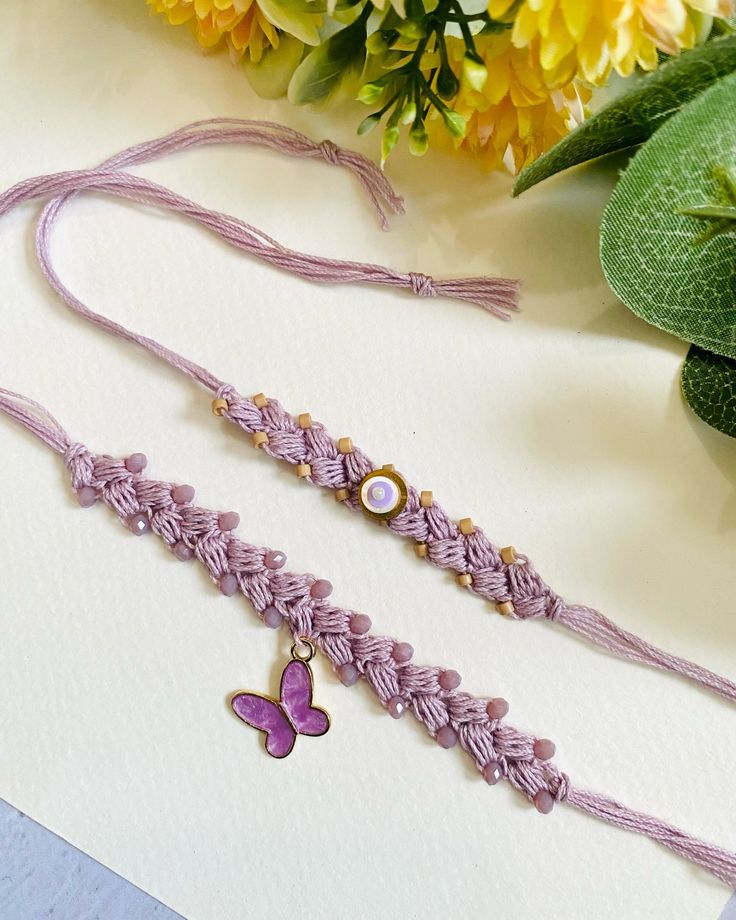 two necklaces on a table with flowers in the background