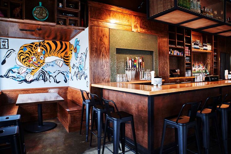 a bar with several stools in front of it and a tiger mural on the wall