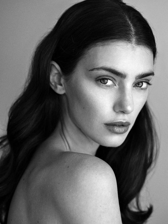 a black and white photo of a woman with long dark hair wearing a strapless top