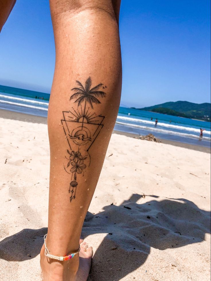 a woman's legs with a tattoo on the beach