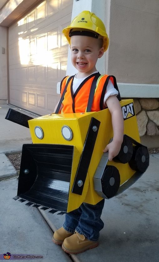 a young boy dressed up as a construction worker holding a large yellow bulldozer