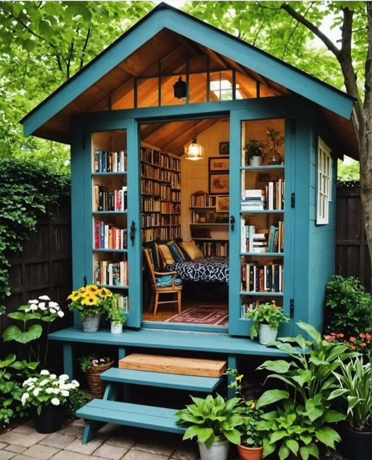 a small blue shed with bookshelves in the front and stairs leading up to it