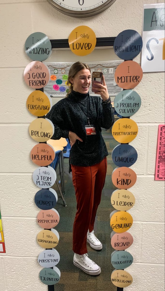 a woman taking a selfie in front of a wall with circles and words on it