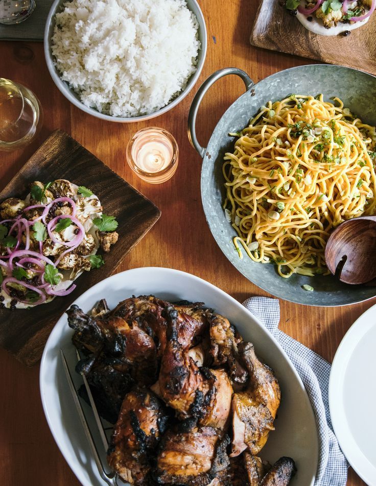 two bowls of food on a table with rice, meat and other foods next to it