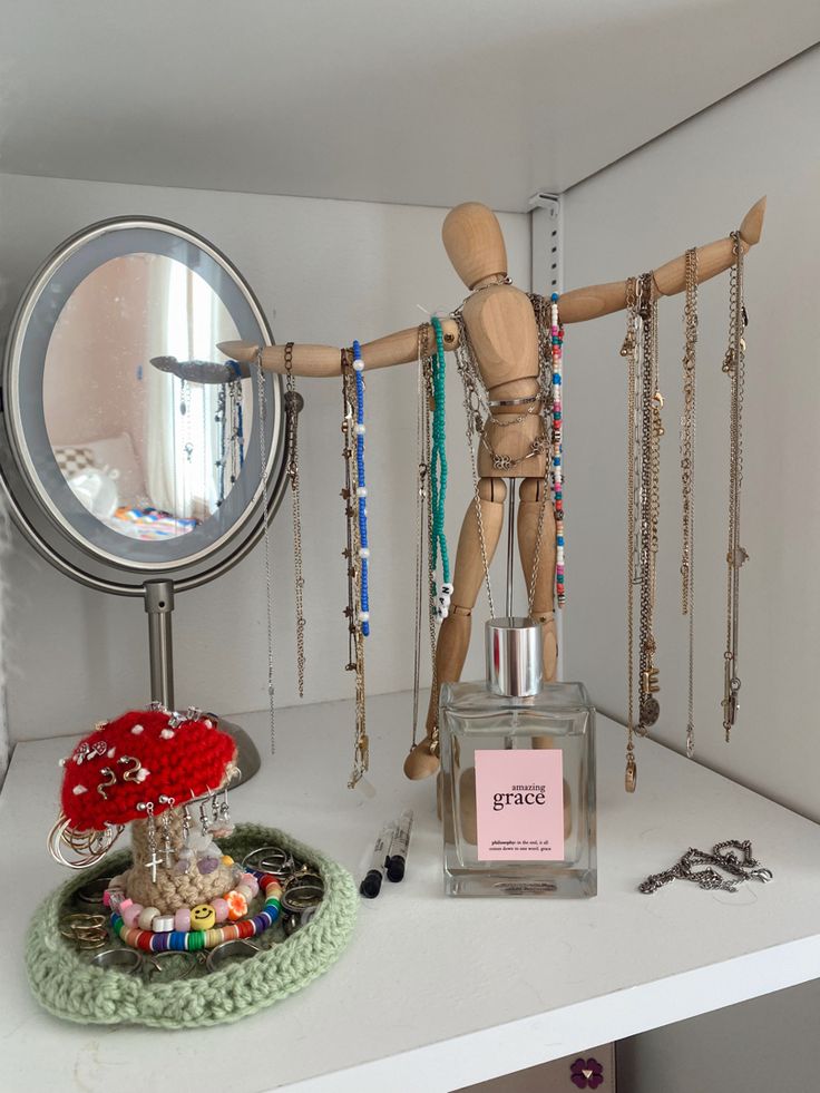 a wooden mannequin standing next to a mirror and jewelry on a counter top