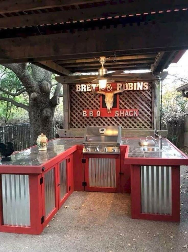 an outdoor bbq with grills and tables under a shade structure that reads great & robin's bbq shack