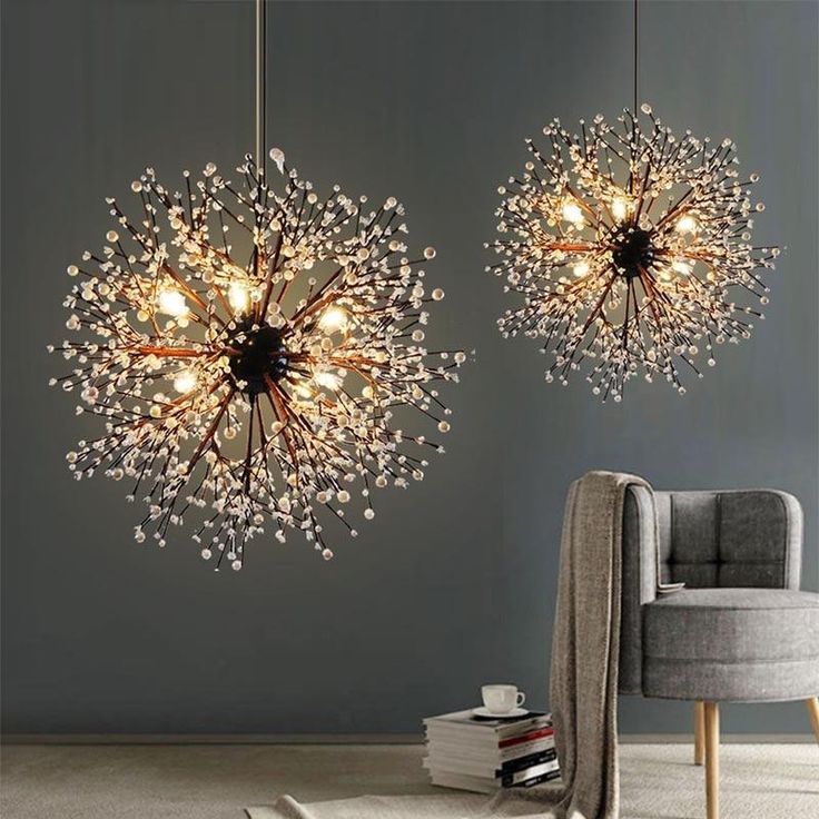 two chandeliers hanging from the ceiling in a room with grey walls and chairs