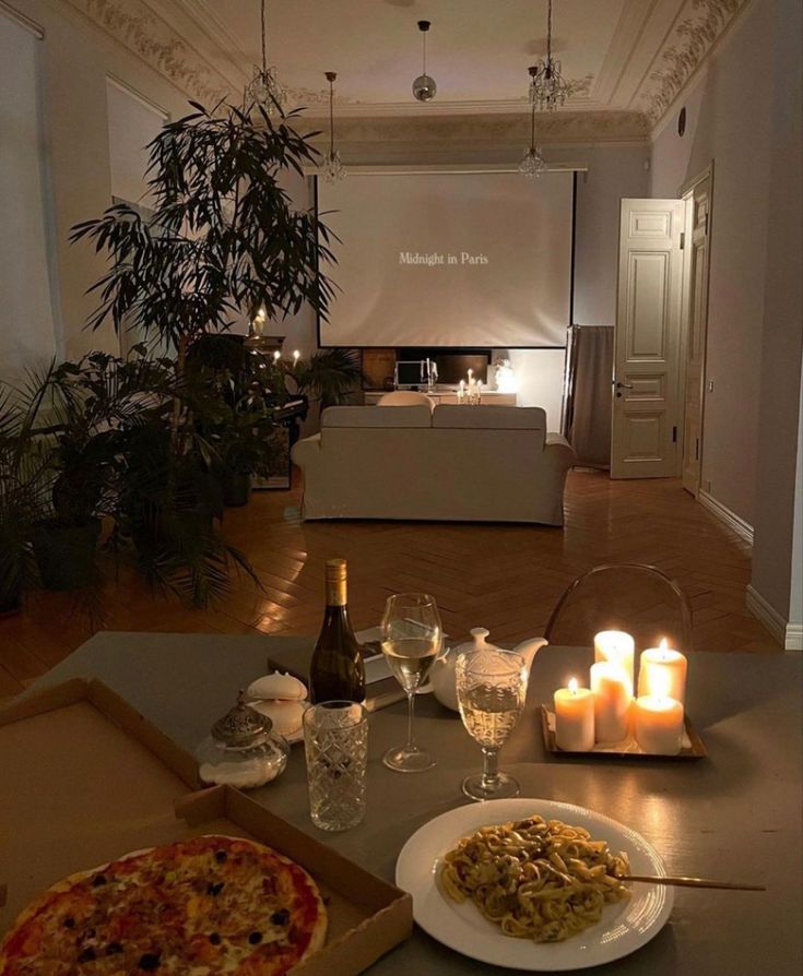 a table with pizza, wine and candles on it