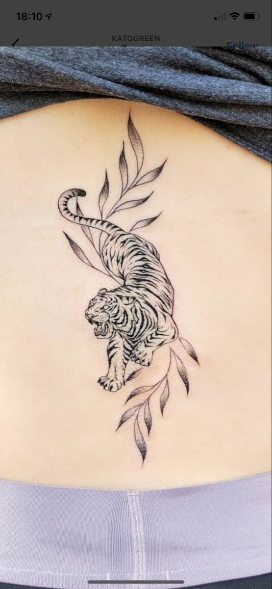 a woman's back with a tiger tattoo on her lower back and the bottom part of her stomach