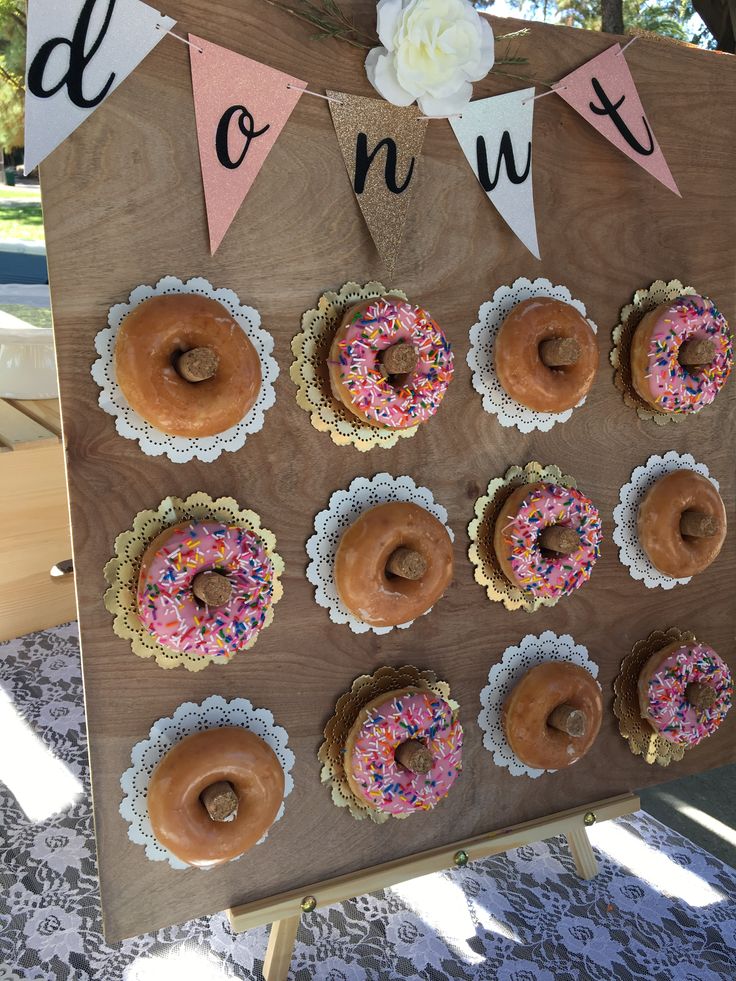 a wooden sign with donuts hanging from it's sides and bunting around them