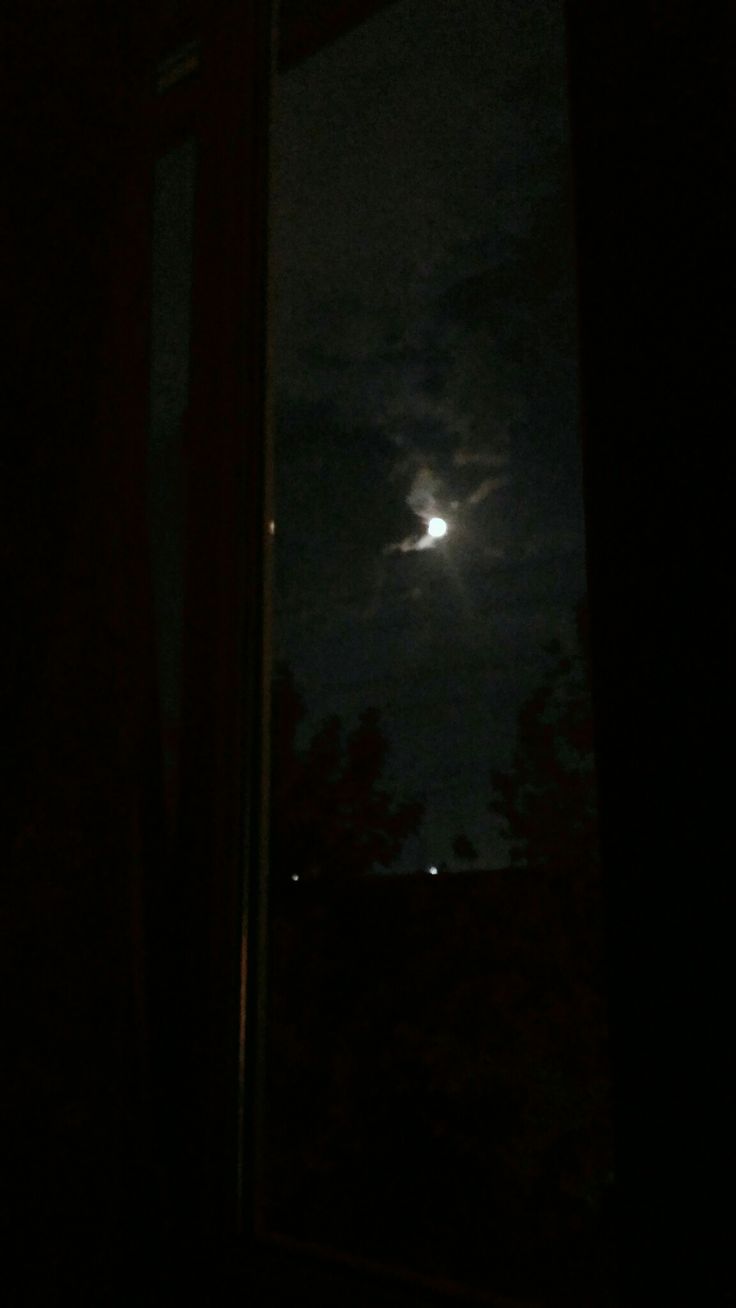 the full moon is seen through an open window