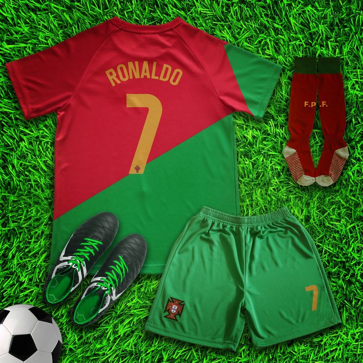 a soccer uniform and shoes laying on the grass next to each other, including one ball