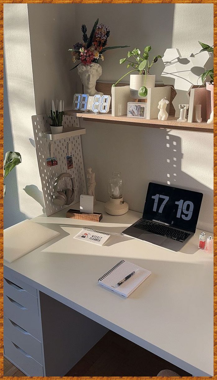 a white desk topped with a laptop computer next to a shelf filled with plants and candles