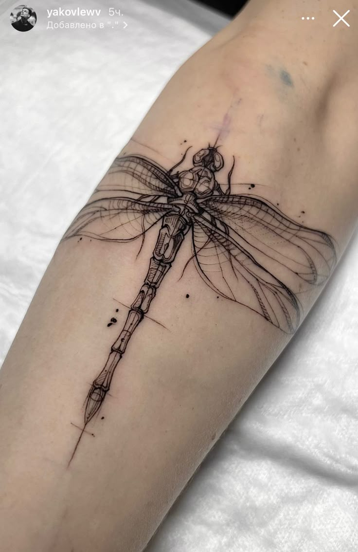 a woman's arm with a dragonfly tattoo on the back of her leg