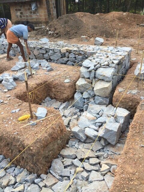 two men are working on the construction of a stone wall in an area that is being built