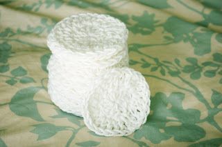 two white crocheted cups sitting on top of a green flowered cloth covered bed