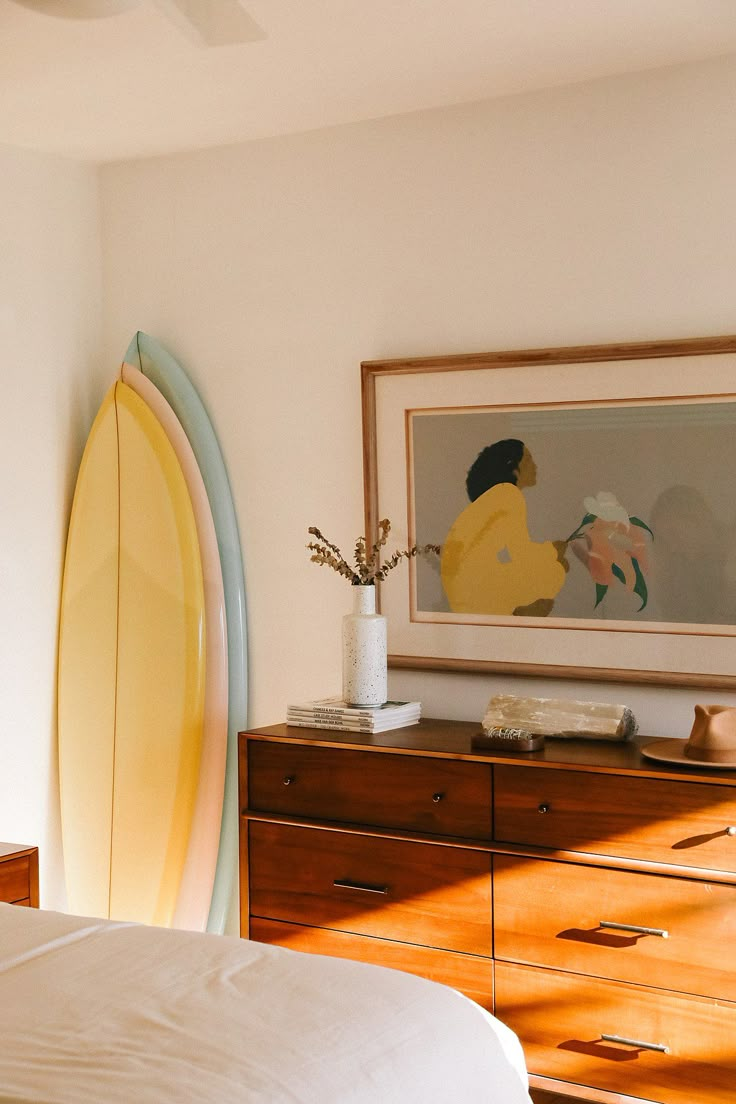 there is a surfboard next to the dresser