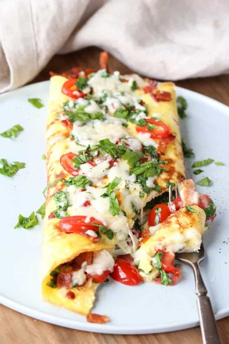 a white plate topped with an omelet covered in cheese and veggies