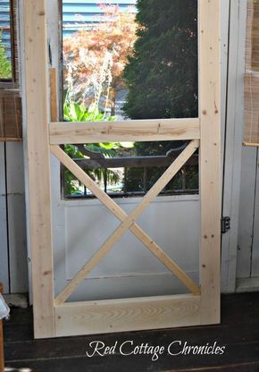 an open wooden door on the side of a house with trees in the back ground