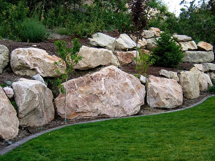 a large rock wall next to a lush green field