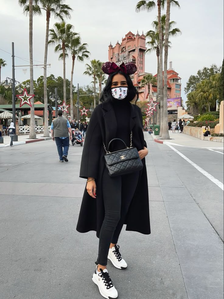 a woman in black is standing on the street with her handbag and sunglasses over her face