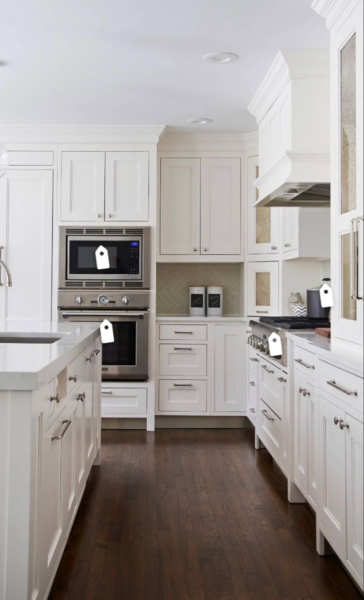 a kitchen with white cabinets and wood floors