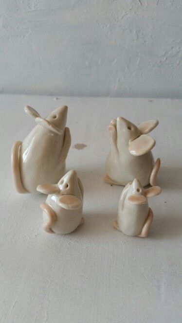 three ceramic figurines of mice sitting next to each other on a white surface