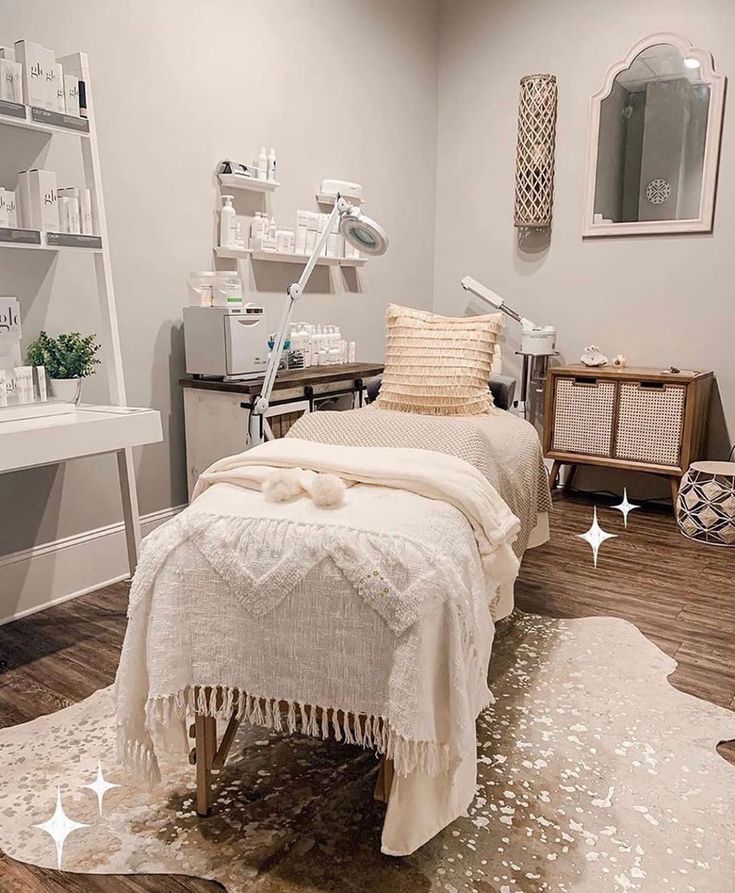 a white bed sitting on top of a wooden floor next to a shelf filled with bottles