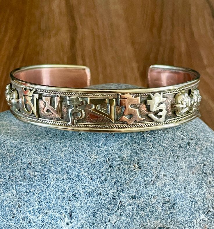 This beautiful Tibetan cuff bracelet is made in Nepal. Size: 18cm - As It's open-ended, would fit most hands Width - 13mm approx Weight - 23 gms approx Material: white metal, copper, brass To fit the bracelet open it up so the gap is wide enough to pass over the narrowest part of your wrist and then squeeze it back into shape until it is a nice comfortable fit. Please note due to this item being handmade there may be some imperfection. Adjustable Symbolic Cuff Bracelet, Adjustable Symbolic Bangle, Adjustable Nickel-free Bronze Bracelet, Adjustable Symbolic Bangle Bracelet, Adjustable Bronze Cuff Bracelet For Festivals, Spiritual Festival Bangle Cuff Bracelet, Adjustable Bronze Cuff Bracelet For Festival, Traditional Adjustable Band Jewelry, Adjustable Engraved Bronze Bracelets