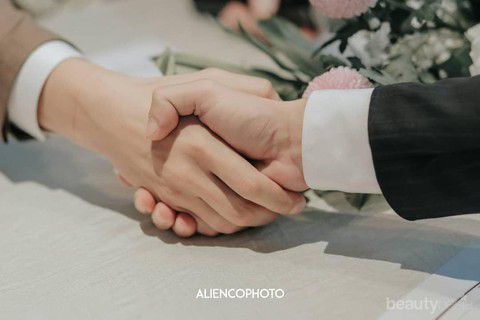 two people holding hands over a table with flowers