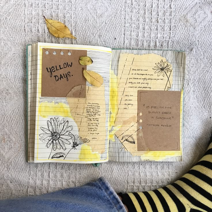 an open notebook with yellow flowers and some writing on the pages next to a woman's legs