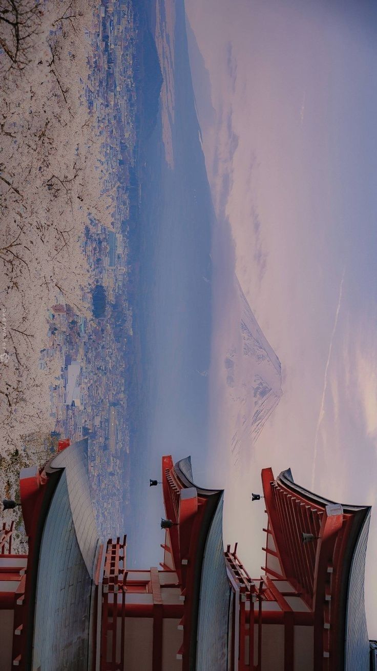 there are many red chairs that are in front of the mountains and clouds behind them