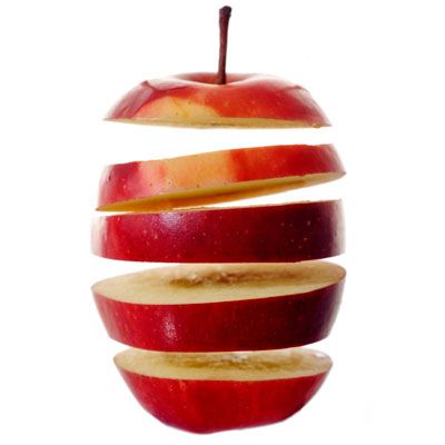 an apple sliced in half with the peel still attached to it's core, on a white background